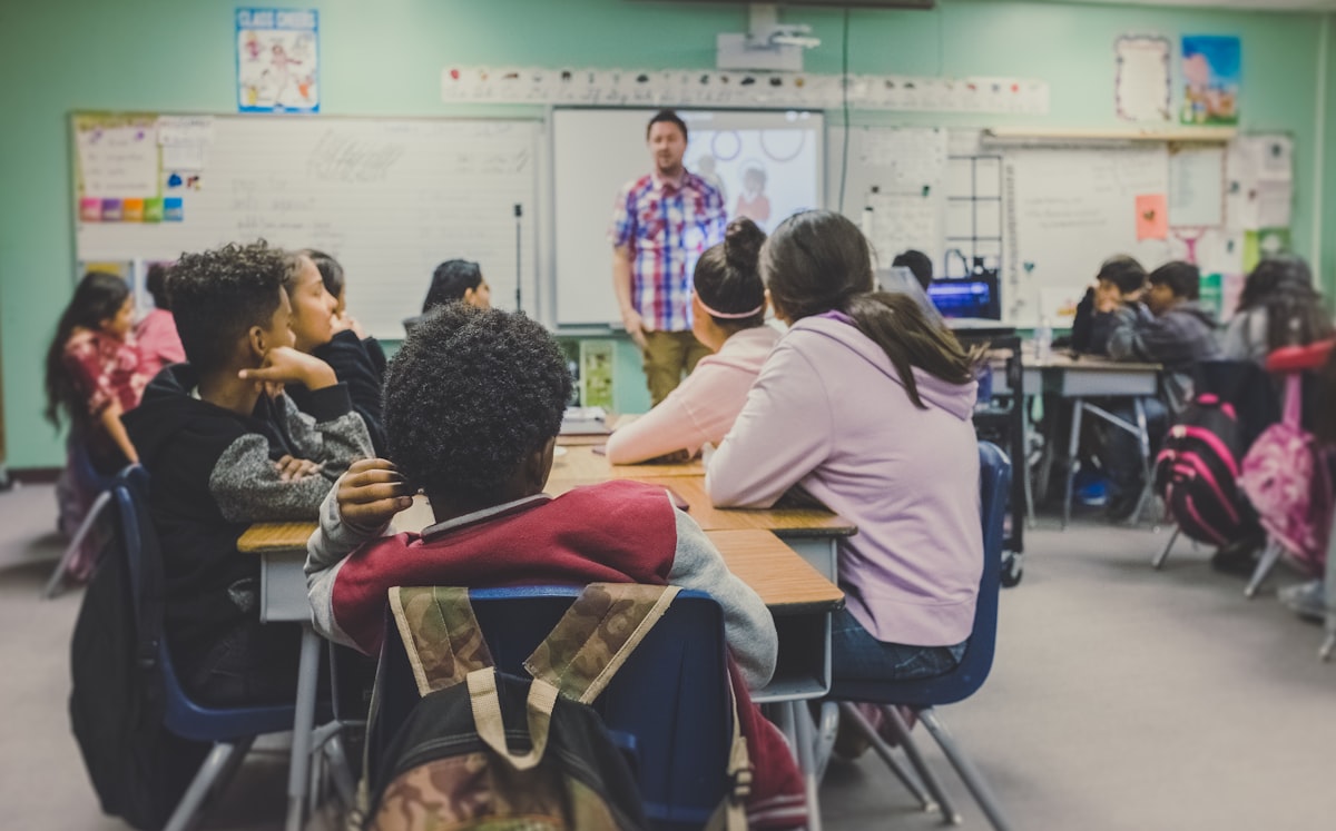 A middle school classroom with students at their desks and a teacher at the front